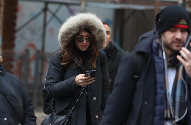 Donna col cappotto e col cellulare in mano